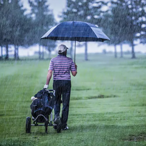 Man golfing with an umbrella